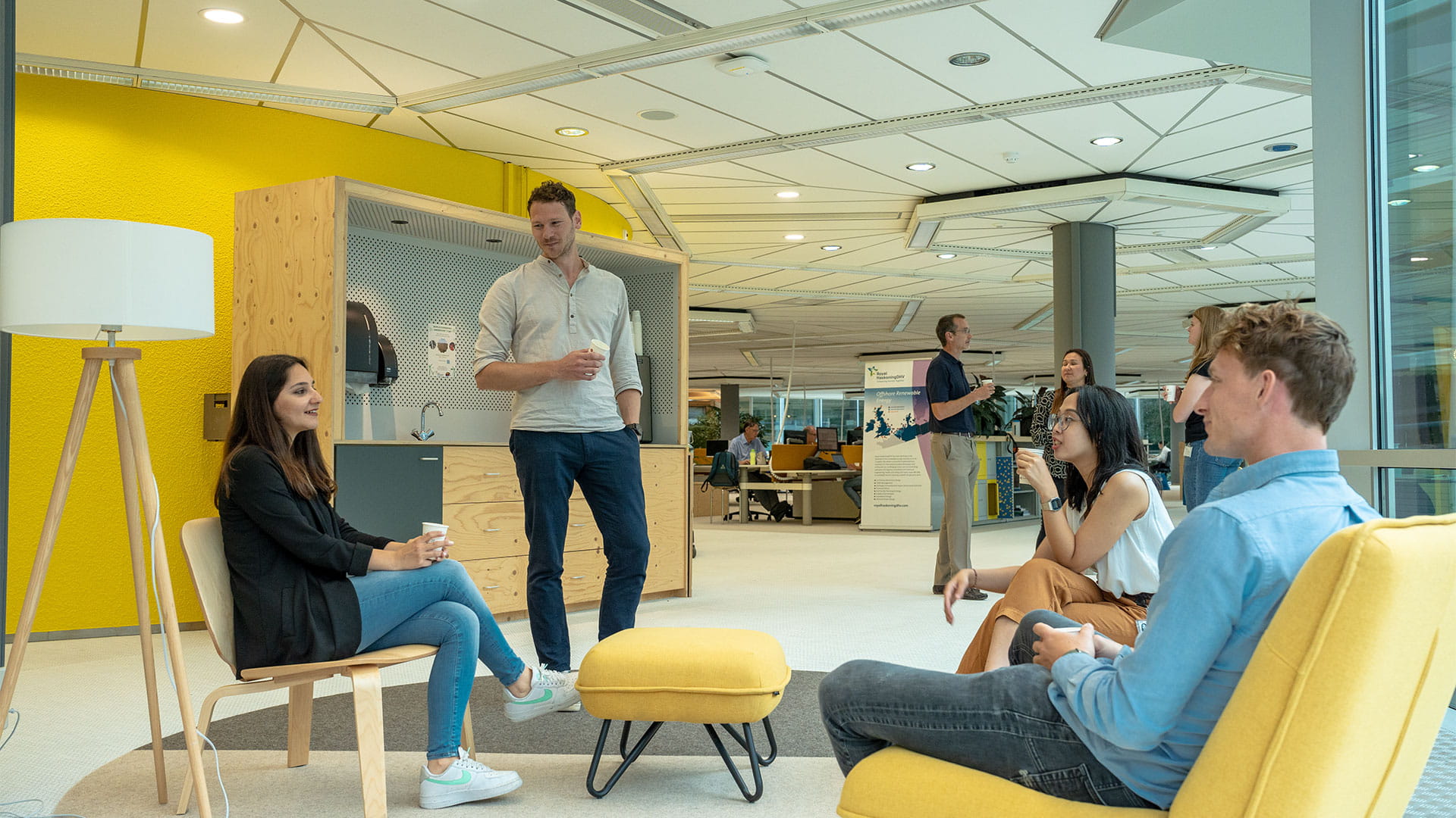 Drie personen in gesprek bij de koffiemachine