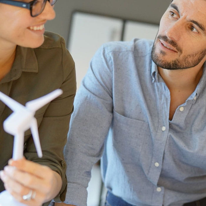 Een vrouw met een groen shirt en een replica van een windmolen en een man met een groen shirt.