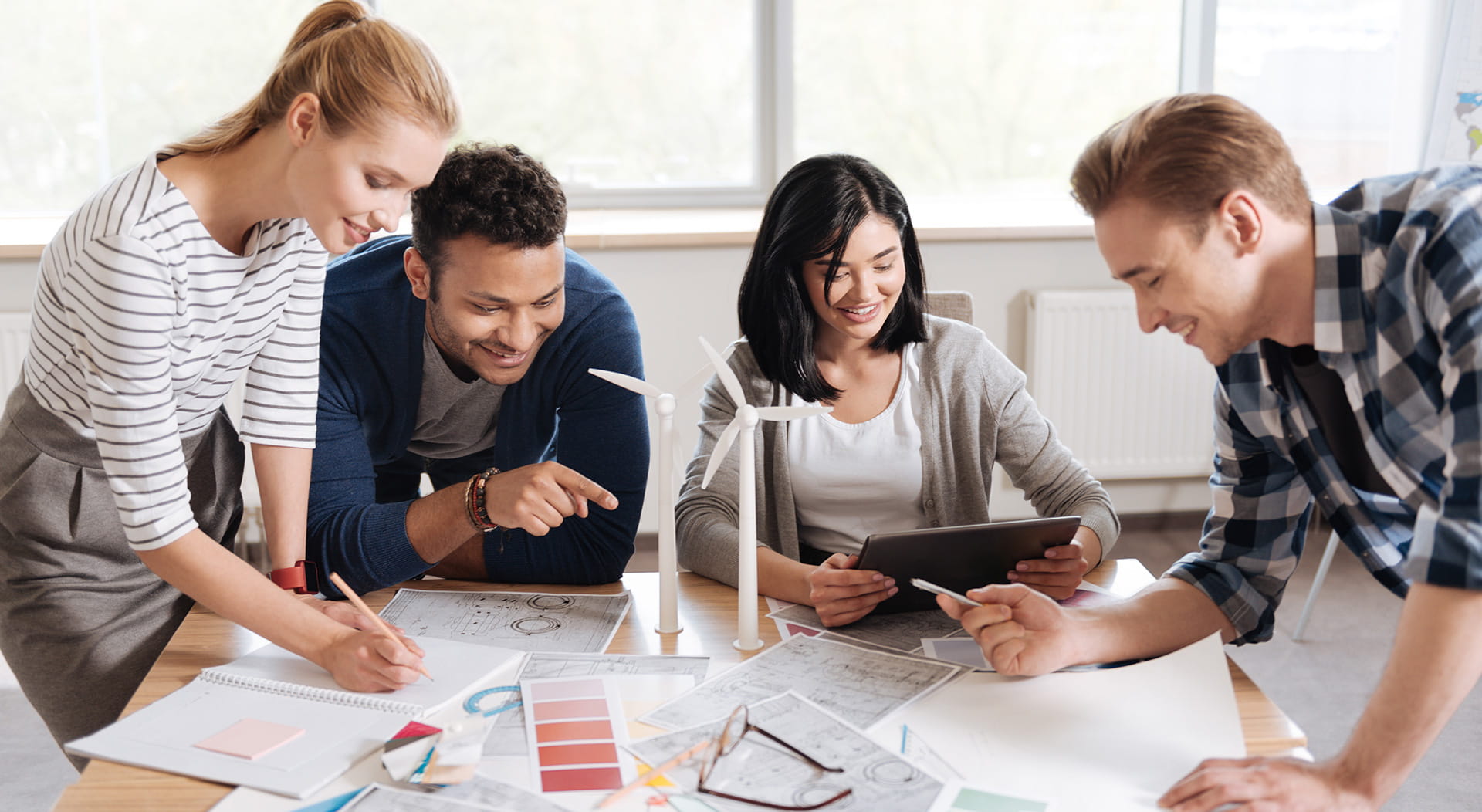 Vier mensen die in overleg zijn en aantekeningen maken.