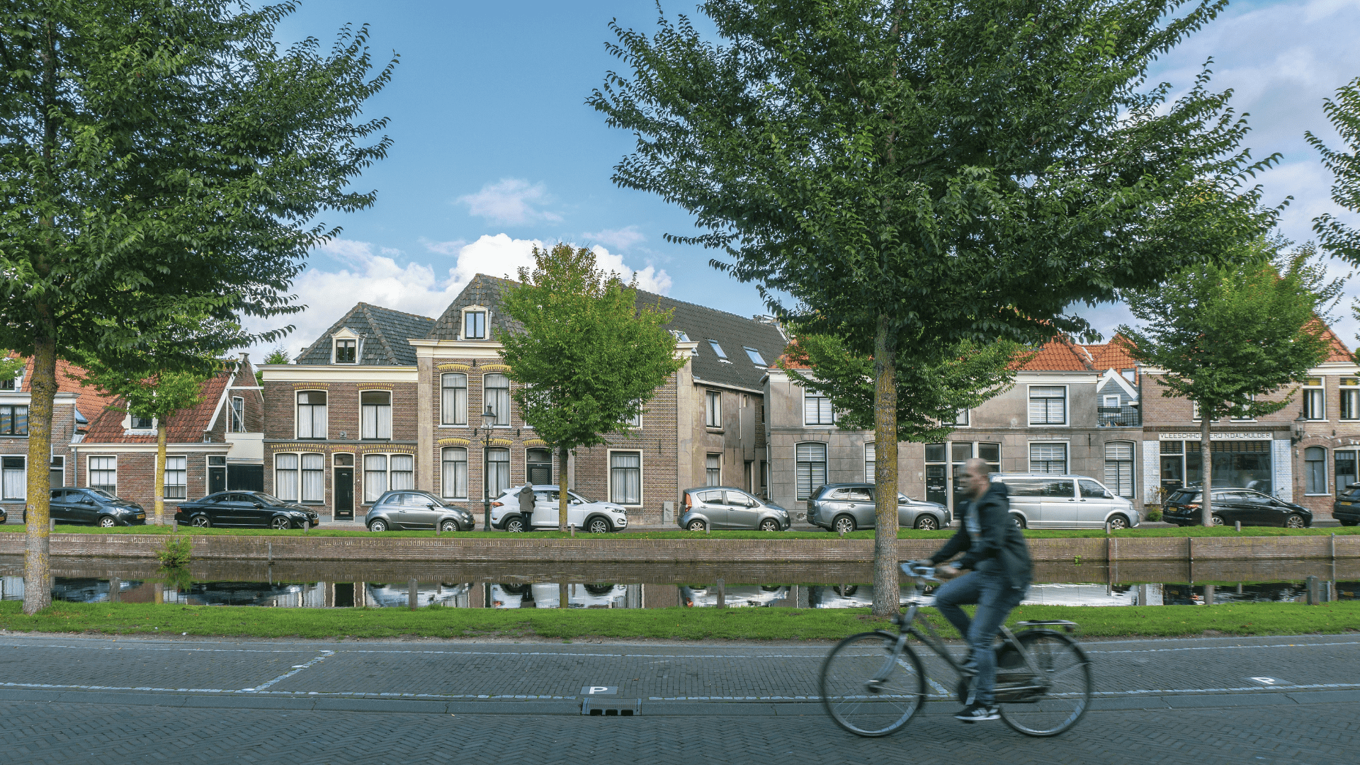 Foto van een kanaal in Haarlem waar iemand langsfietst