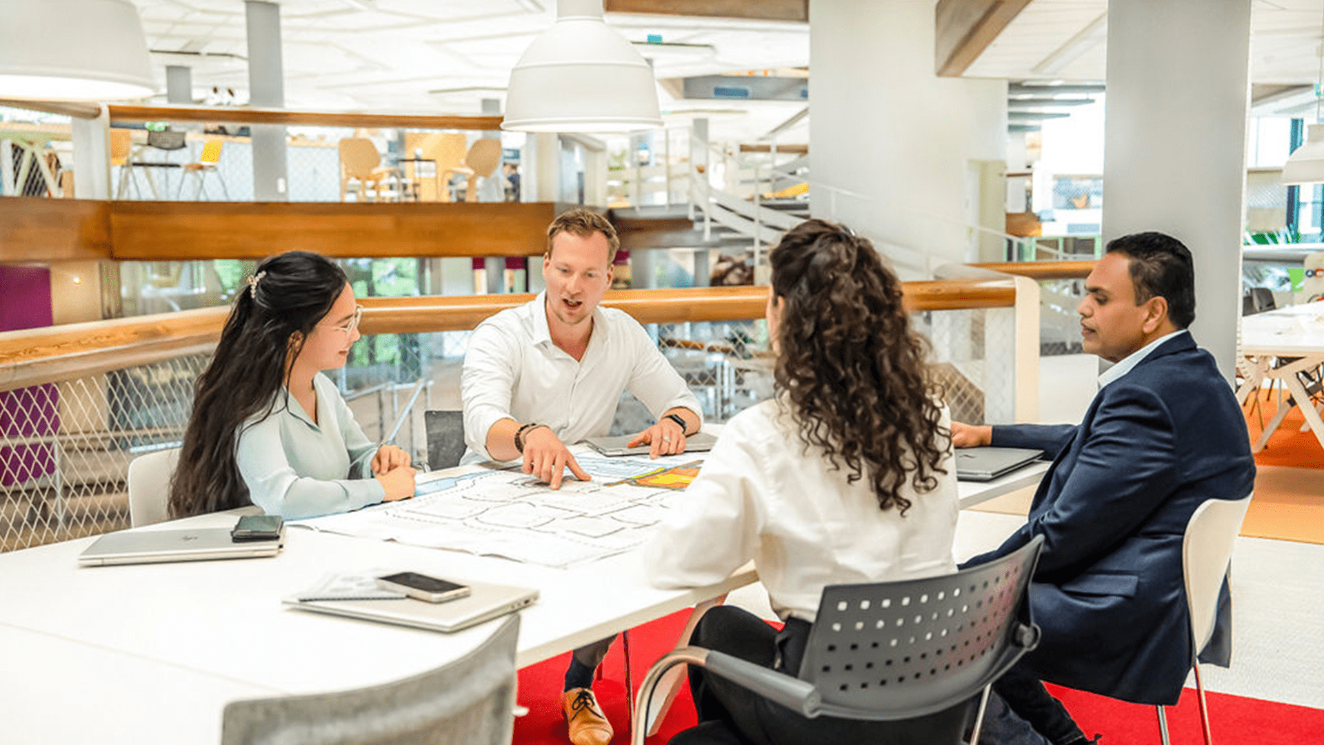 vier mensen die een gesprek houden aan een tafel.