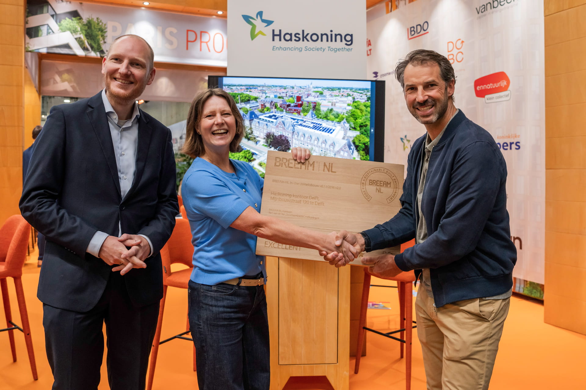 Drie mensen nemen het BREEAM Excellent-certificaat in ontvangst