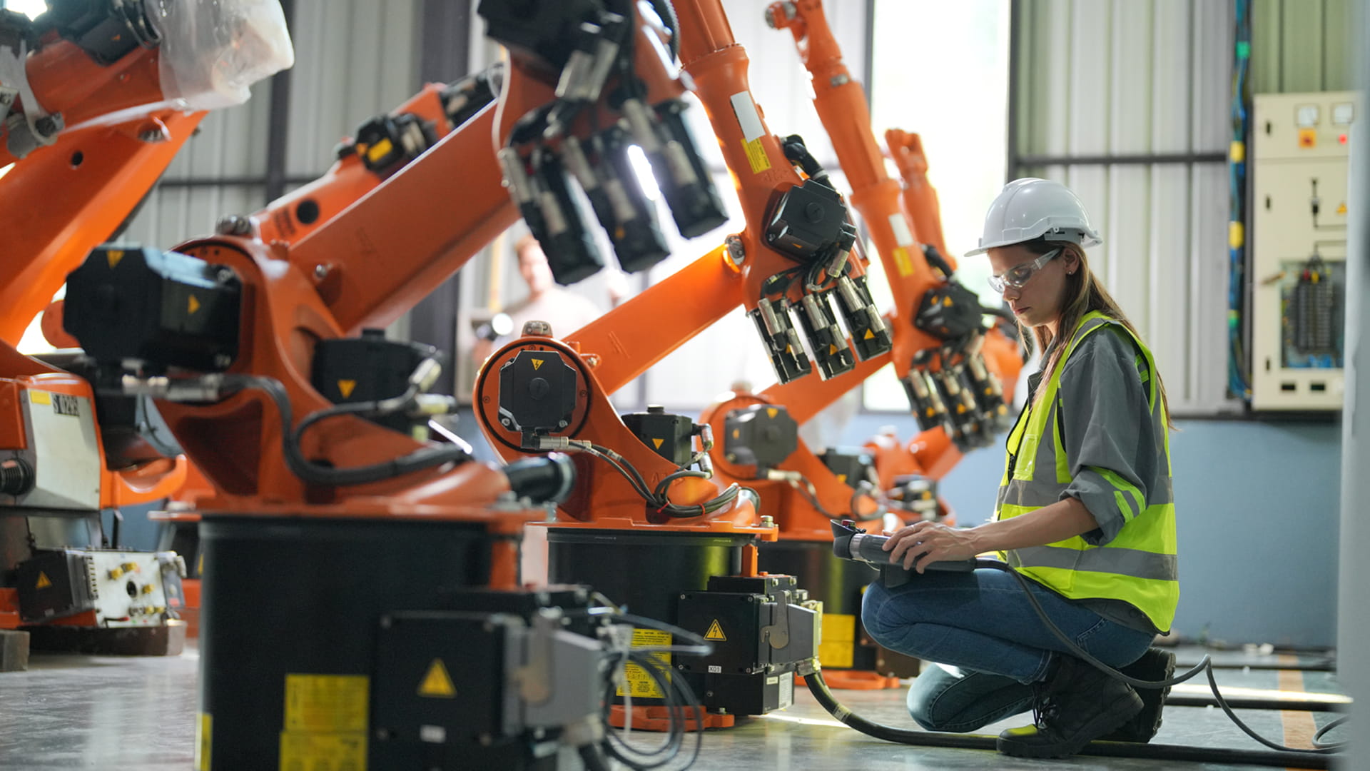 Ingenieur inspecteert robotarmen in een geavanceerde industriële faciliteit.