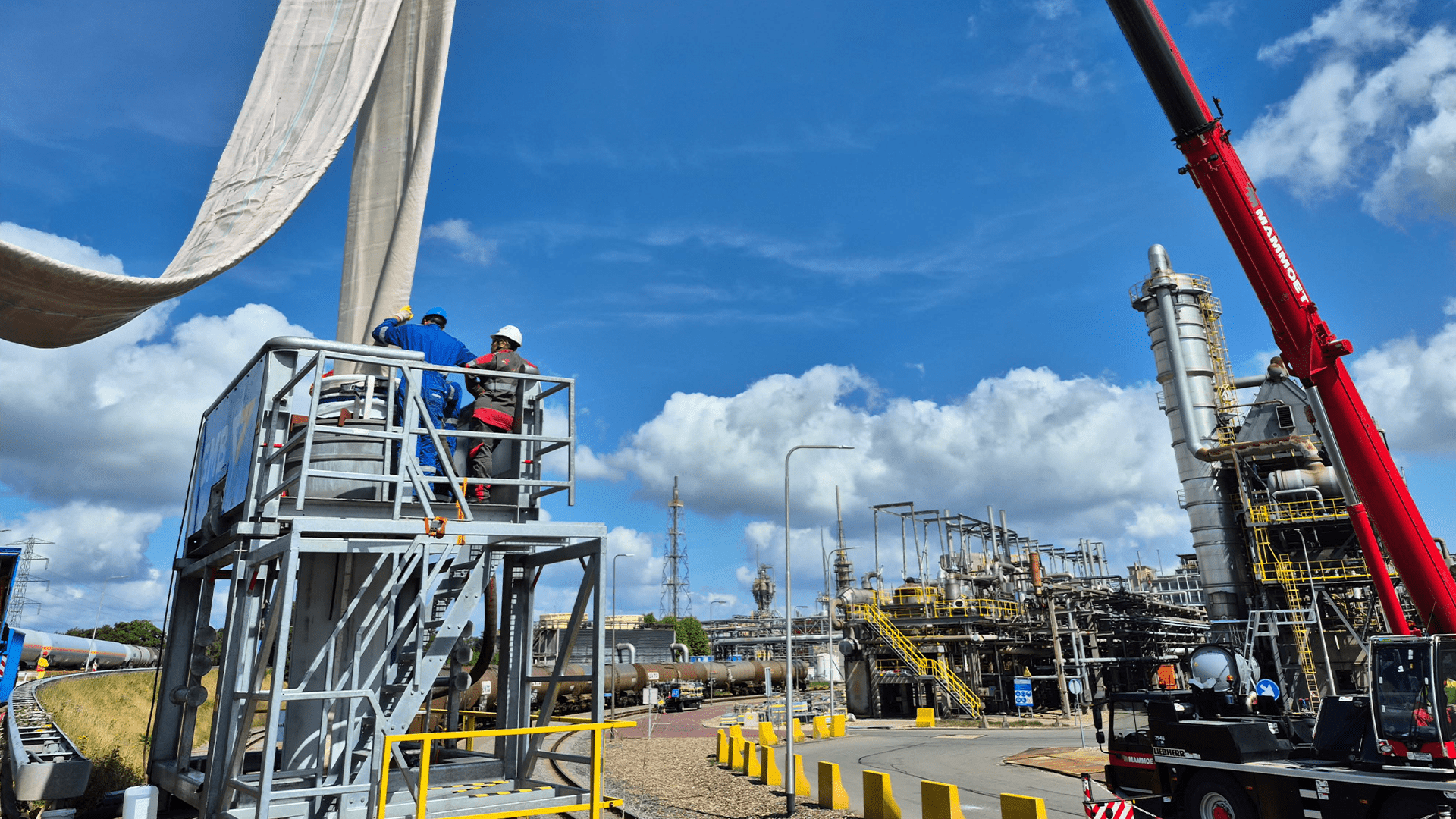 Werkers op steigers bij industriële site