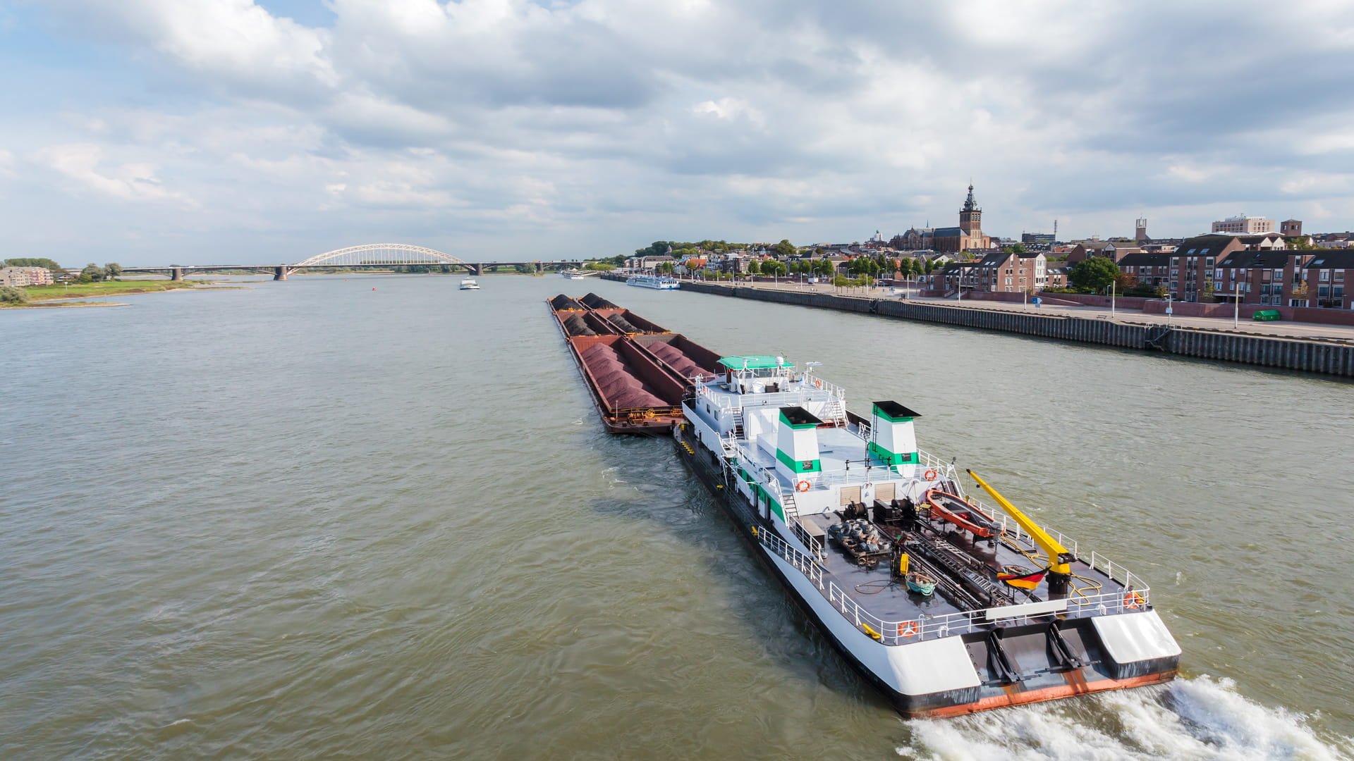 Een vrachtboot op de rivier de Waal die langs de stad Nijmegen vaart