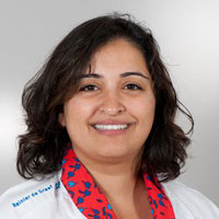 Een persoon met donker haar die een witte jas draagt