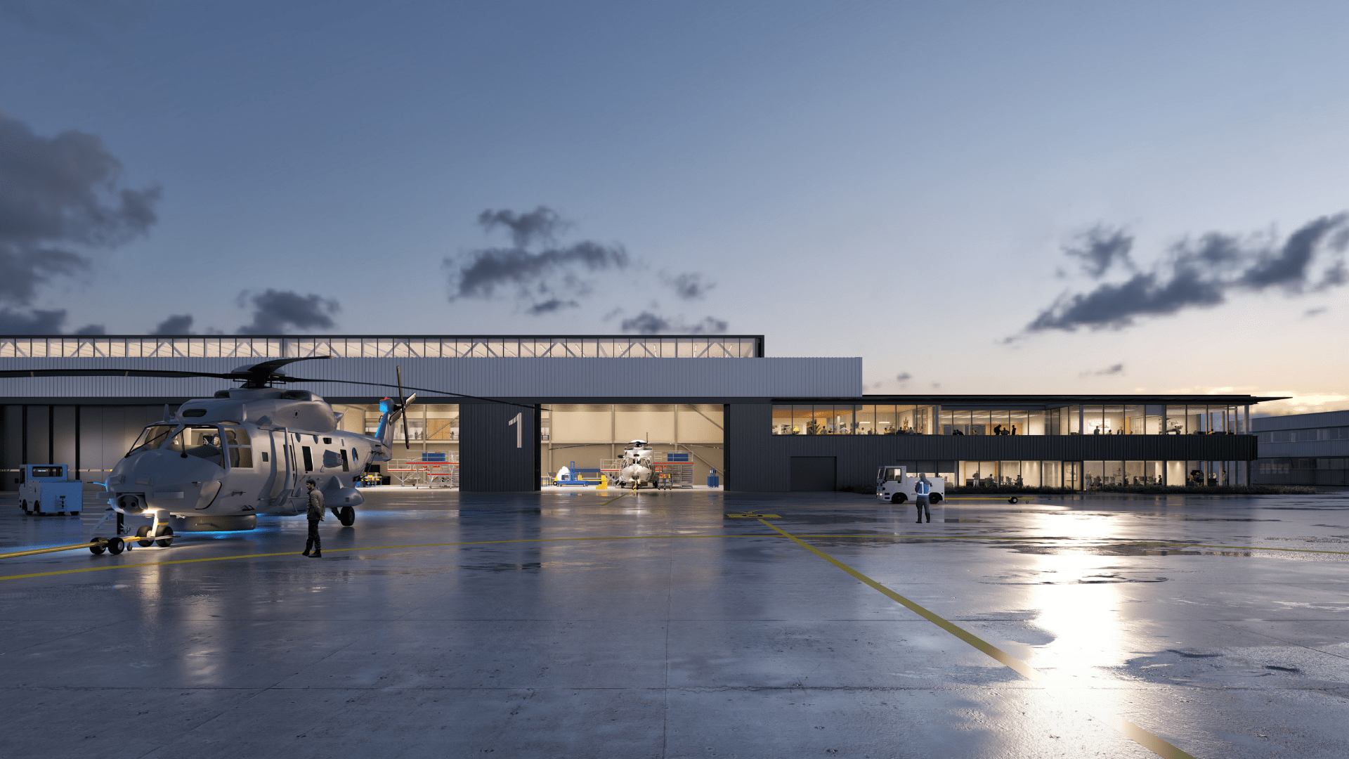 Helikopter op een nat platform bij een verlichte hangar, met werkruimtes zichtbaar achter glas in de avondschemering.