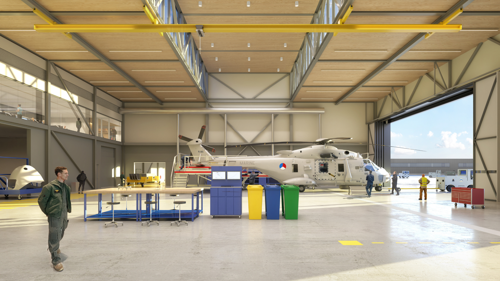 Ruime onderhoudshal met een militaire helikopter, werktafels, gereedschap en personeel in een lichte, industriële ruimte.