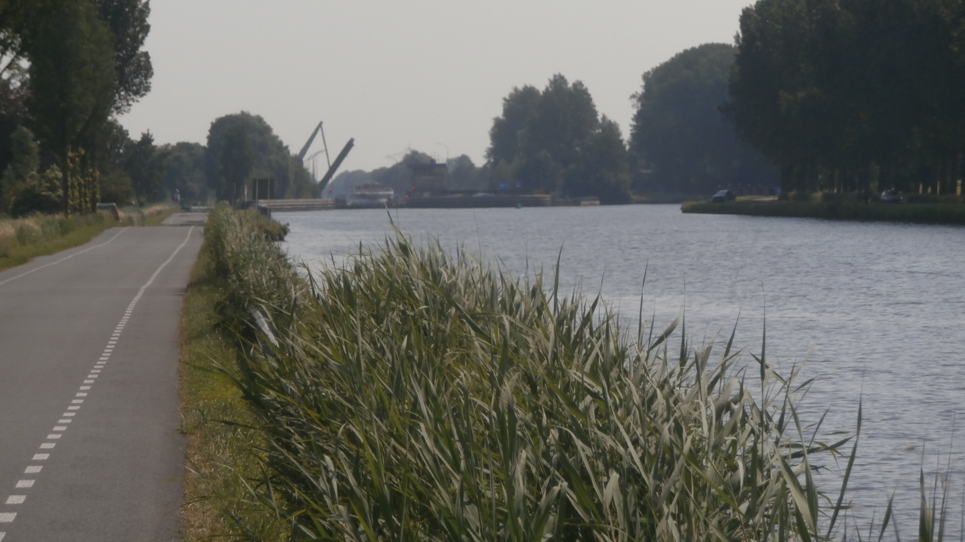 Een 118 kilometer lange vitale vaarweg die Noord-Nederland met Amsterdam, Rotterdam en Duitsland verbindt, hier vastgelegd langs een groene oever op een bewolkte dag.