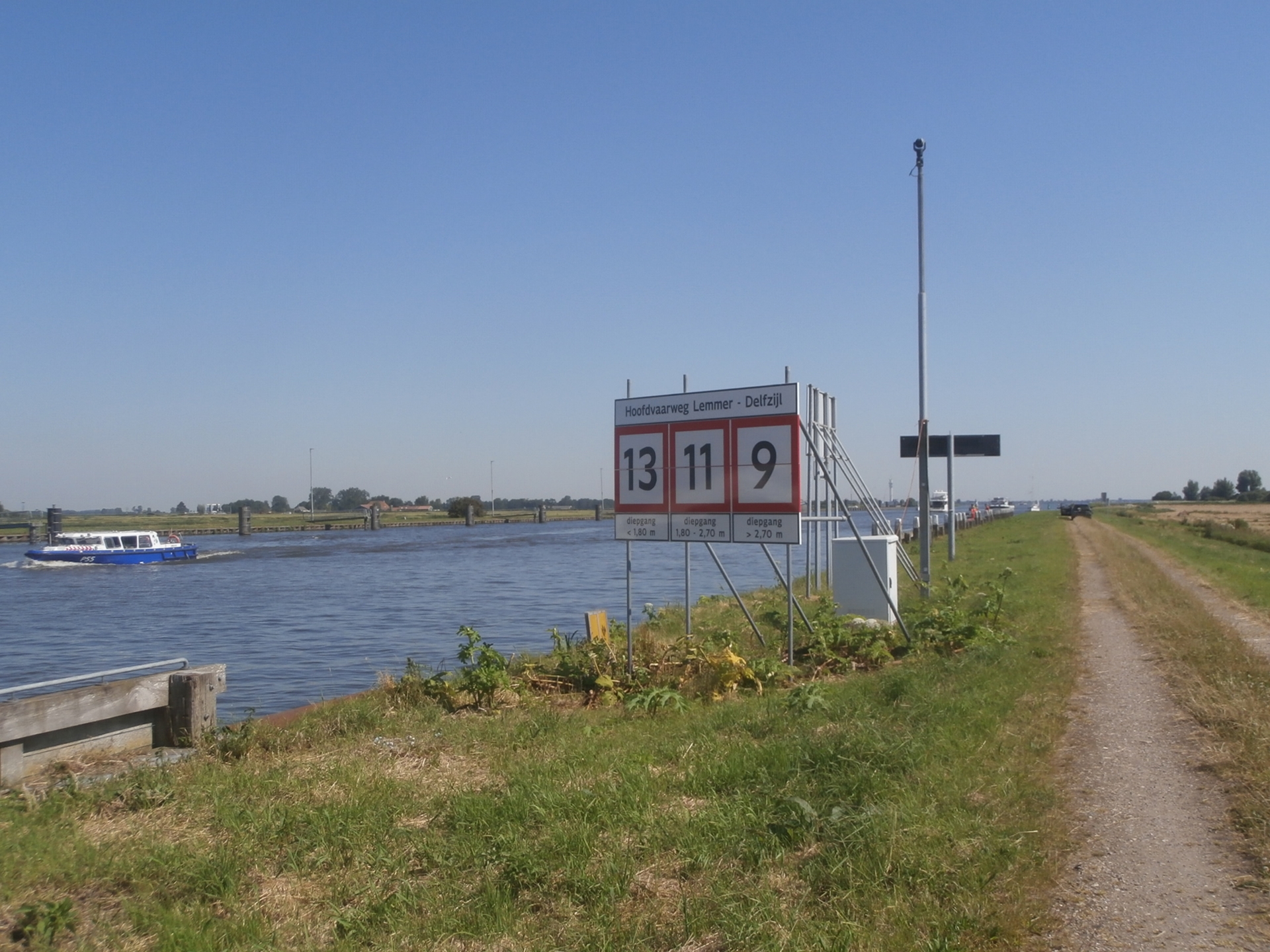 Informatieborden langs de zonnige oever van de Hoofdvaarweg Lemmer-Delfzijl geven cruciale diepganggegevens voor een veilige en vlotte doorstroming van de beroepsvaart.