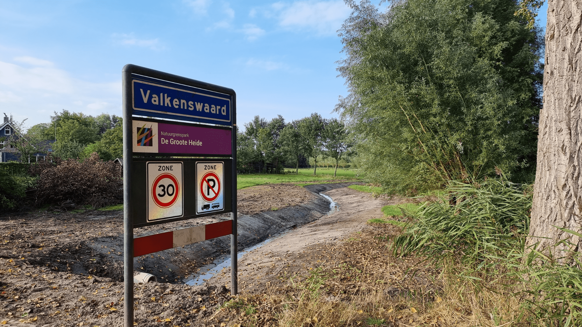 Afbeelding van een bord daarop de plaatsnaam Valkswaard met op de achtergrond de herinrichting van de Tongelreep