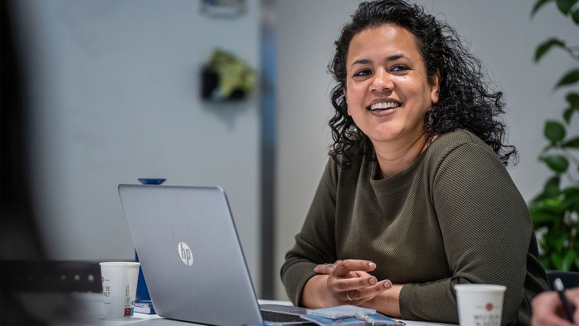 Vrouw in vergaderruimte met laptop en koffie